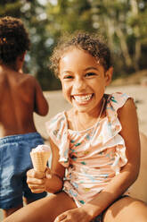 Porträt eines glücklichen Mädchens mit einem Eis in der Hand an einem sonnigen Tag - MASF32639