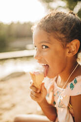 Girl looking sideways while licking ice cream on sunny day - MASF32640