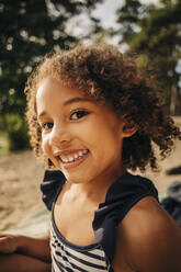 Porträt eines glücklichen Mädchens mit lockigem Haar im Urlaub - MASF32644