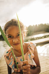 Girl making facial expression while holding blade of grass - MASF32645