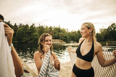 Frauen mit Handtuch unterhalten sich am See im Urlaub - MASF32682