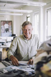 Porträt eines lächelnden männlichen Designers, der in einer Werkstatt sitzt - MASF32732