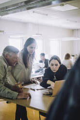 Male and female fashion designers looking at laptop during meeting at workshop - MASF32740