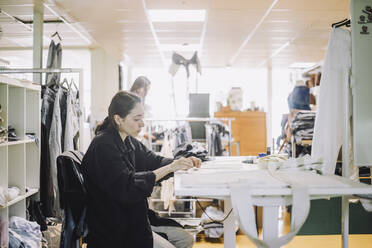 Seitenansicht einer Modedesignerin bei der Arbeit im Atelier - MASF32742