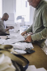 Männlicher Modedesigner beim Verpacken von Stoffen während der Arbeit im Atelier - MASF32784