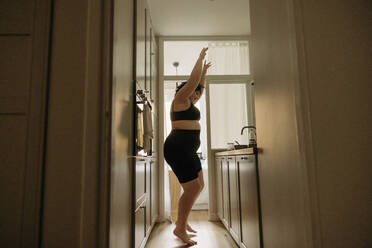 Young woman wit arms raised enjoying dance in kitchen at home - MASF32851