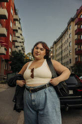 Portrait of young voluptuous woman standing against buildings - MASF32894