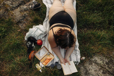Hohe Winkel Ansicht der üppigen Frau Lesen Buch, während auf Handtuch liegen - MASF32922