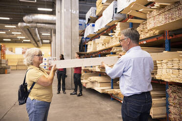 Senior man and woman choosing plank on rack at hardware store - MASF32931