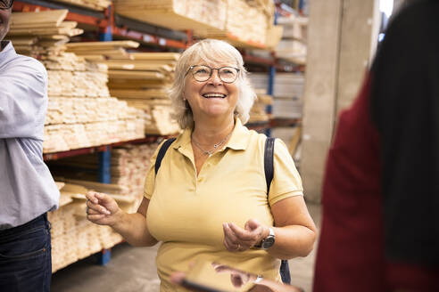 Glückliche ältere Frau mit Brille, die eine Verkäuferin in einem Eisenwarenladen ansieht - MASF32937