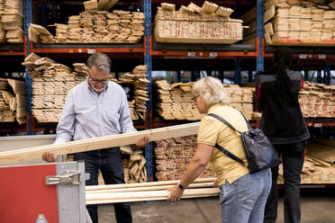 Senior customers examining and loading planks in trailer while shopping at hardware store - MASF32983