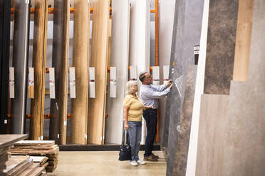 Senior male and female customer buying laminated wooden boards at hardware store - MASF33010