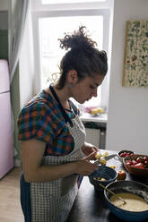 Frau mit Schürze schneidet Früchte bei der Zubereitung von Speisen in der Küche - MASF33037