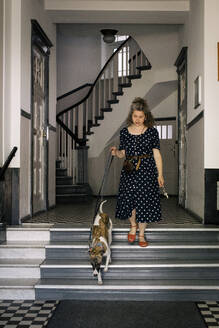 Frau geht mit Hund die Treppe hinunter - MASF33050