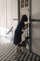 Frau verriegelt Haustür, während sie mit Hund steht - MASF33051
