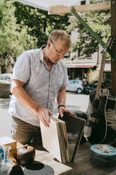 Älterer Mann wählt Schallplatten aus, die in der Nähe eines Flohmarktstandes stehen - MASF33126