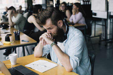 Worried businessman working on laptop at desk in workplace - MASF33162