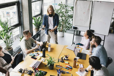 High angle view of male and female computer programmers discussing in meeting at office - MASF33174