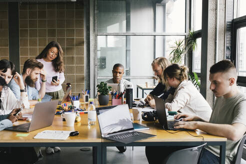 Multirassische Geschäftskollegen arbeiten an Laptops am Schreibtisch in einem Startup-Unternehmen - MASF33180