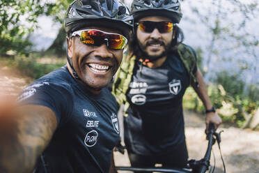 Glücklicher männlicher Radfahrer, der ein Selfie mit einem Freund macht - MASF33211
