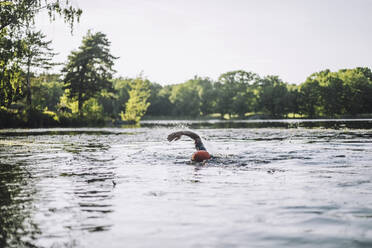 Mature man practicing freestyle swimming in lake - MASF33242