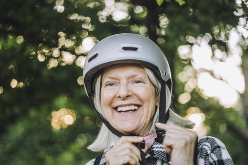 Happy senior woman looking away wearing sports helmet - MASF33270