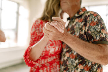 Älteres Paar hält sich an den Händen und tanzt zusammen im Unterricht - MASF33310