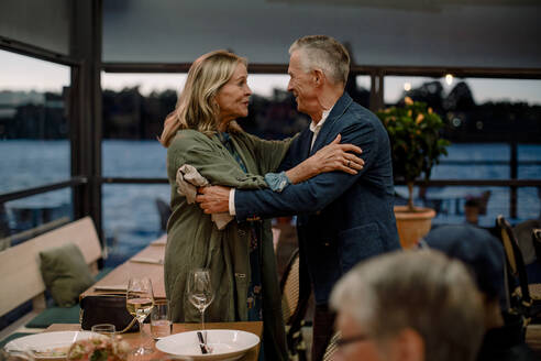 Lächelndes älteres Paar, das sich im Restaurant begrüßt - MASF33338