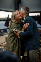 Lächelnde ältere blonde Frau umarmt Mann im Restaurant - MASF33339