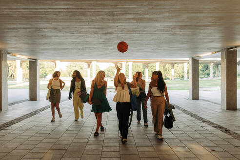 Teenager-Mädchen wirft Basketball beim Spaziergang mit Freundinnen unter einer Brücke - MASF33374