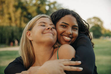 Happy teenage girl hugging female friend with eyes closed - MASF33408