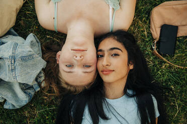 Portrait of teenage girls lying together on grass at park - MASF33416