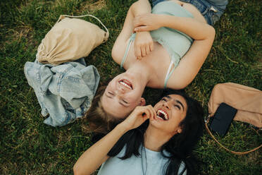 Cheerful teenage girls lying together at park - MASF33417