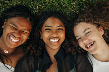 Porträt von glücklichen Teenager-Mädchen, die lachend im Gras liegen - MASF33418