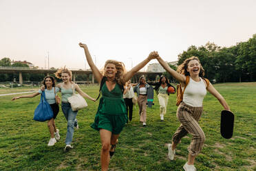 Unbeschwerte Teenager-Mädchen in voller Länge, die zusammen im Park laufen - MASF33445