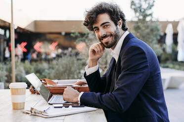 Handsome businessman with laptop at table working from cafe - EBBF07032