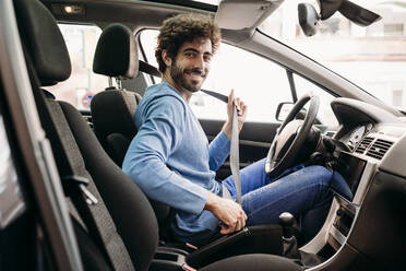 Smiling man wearing seat belt sitting in car - EBBF07128