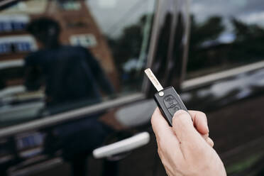 Hand of man unlocking car using key - EBBF07130