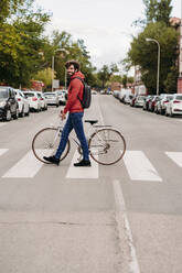 Mann überquert Straße mit Fahrrad in der Stadt - EBBF07147