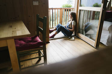 Glückliche junge Frau in der Tür sitzend - GIOF15614