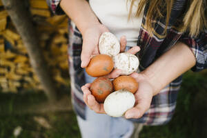Hände einer Frau halten braune und weiße Eier - GIOF15637
