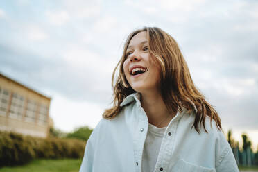 Cheerful teenage girl with blond hair wearing denim shirt - MDOF00238