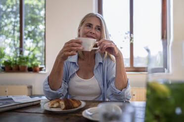 Nachdenkliche reife Frau mit Kaffeetasse am Tisch sitzend - RIBF01222