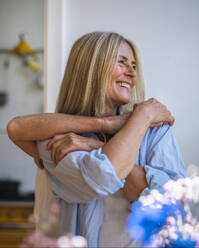Happy woman with friend hugging from behind at home - RIBF01319