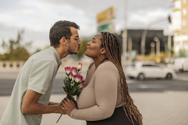 Young couple puckering with bouquet of flowers at footpath - JCCMF08155