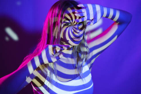 Young woman with illuminated swirl pattern in front of wall - JSMF02495