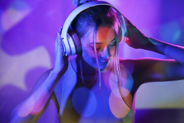 Frau mit Kopfhörern vor einer Wand, die Musik hört - JSMF02501