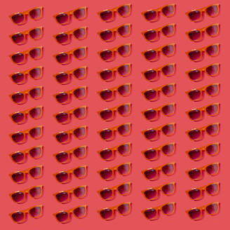 Pattern of old-fashioned sunglasses flat laid against red background - GIOF15640