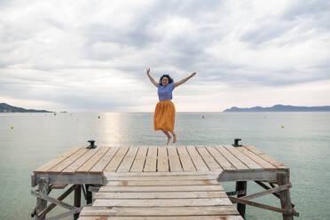 Glückliche Frau springt auf dem Steg vor dem Meer - JOSEF14801