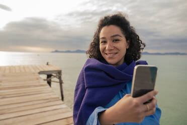 Frau mit Smartphone macht Selfie auf Steg am Meer - JOSEF14818